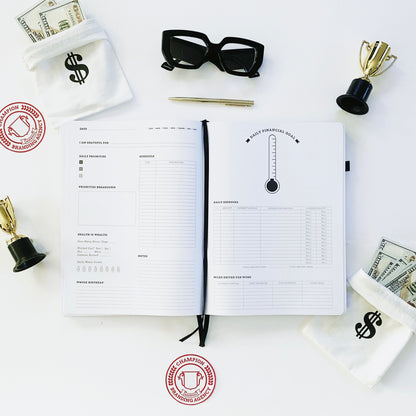 Daily planning page of black Ready Set Win productivity planner. It is flat-laid to the daily page that features dates, a brain dump section, a schedule, a health section, a birthday, notes, and a financial goal page including daily expenses and other features. It is surrounded by small trophies, small money bags with hundred dollar bills, also a gold pen, black frame blue light glasses, and Champion Branding Agency logo stickers.